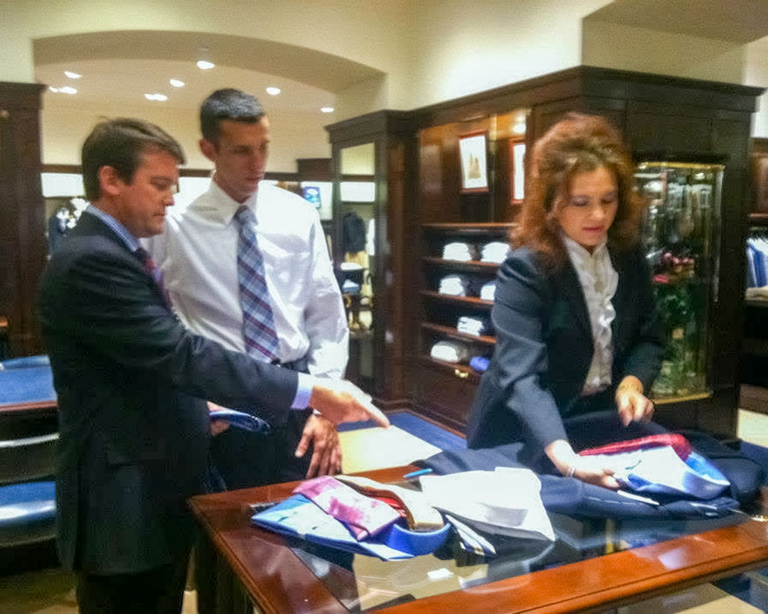 Staff helping a participant select shirts and ties during a fitting