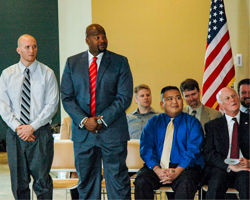 Veterans standing with program supporters at a Boots to Suits event