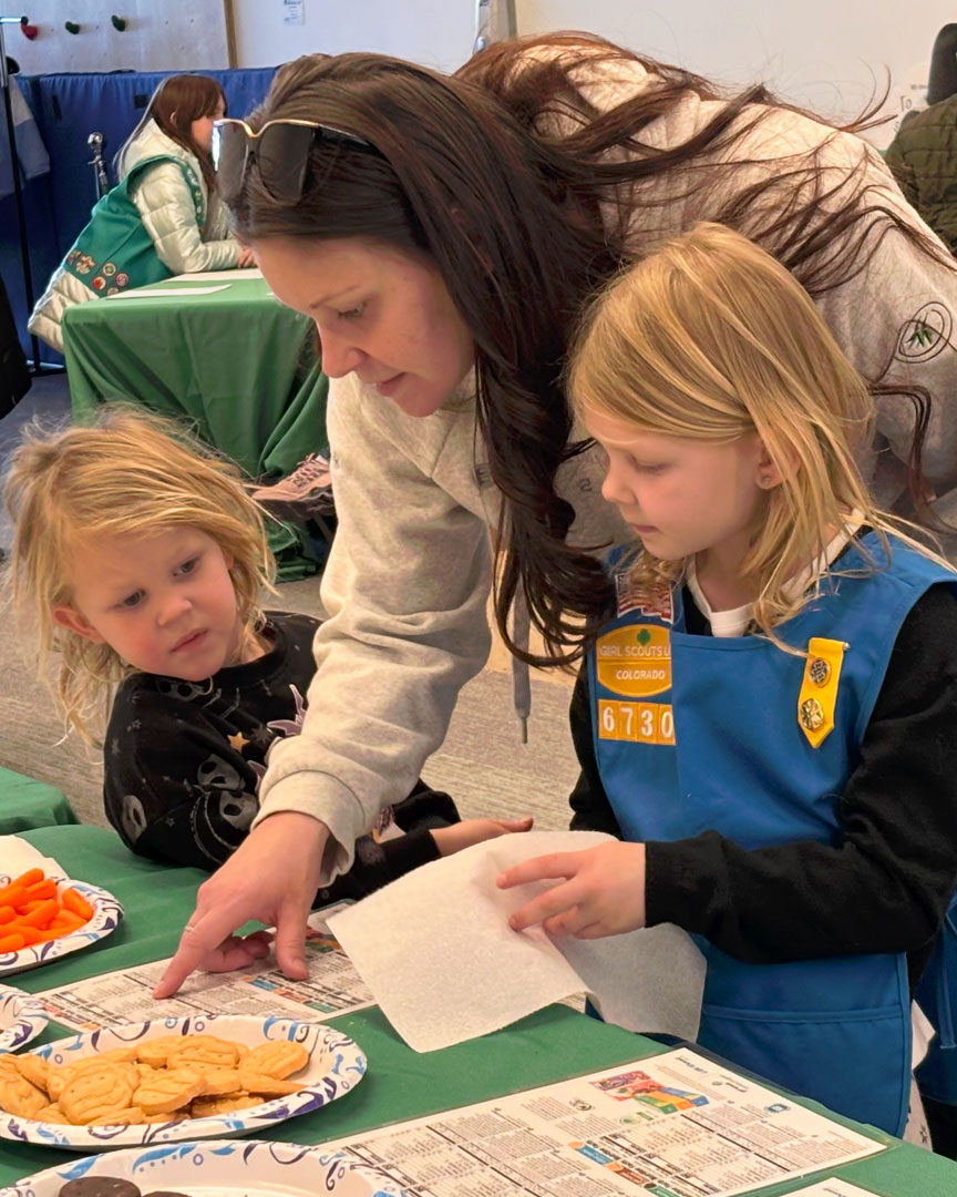 A parent and Girl Scout reading nutrition labels at an activity table