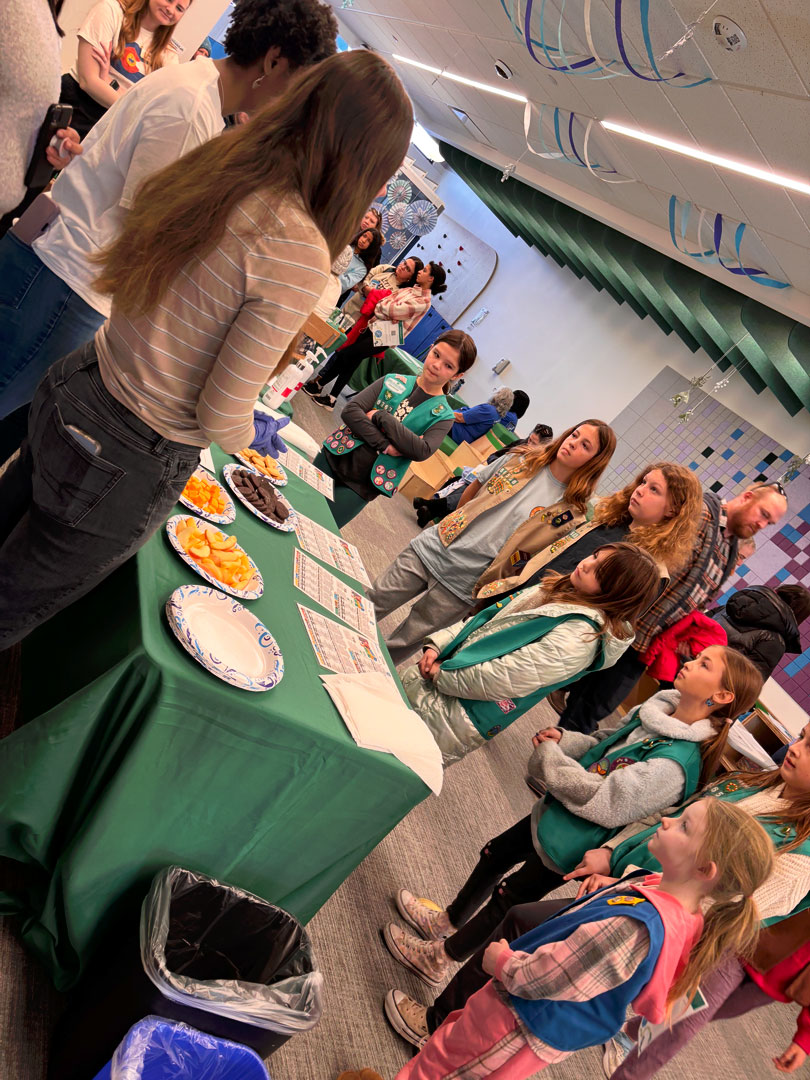 Girl Scouts gathered around a snack table during a health education session