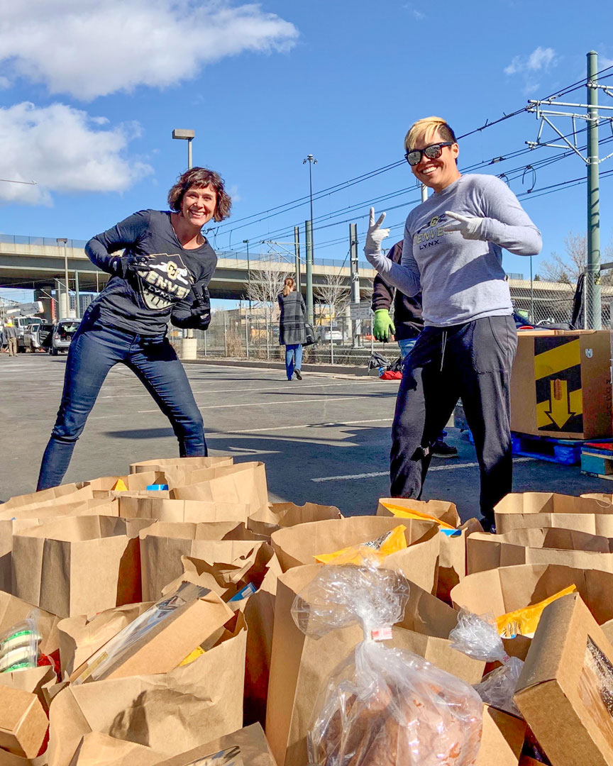 Volunteers behind rows of packed grocery bags at a mobile food bank distribution