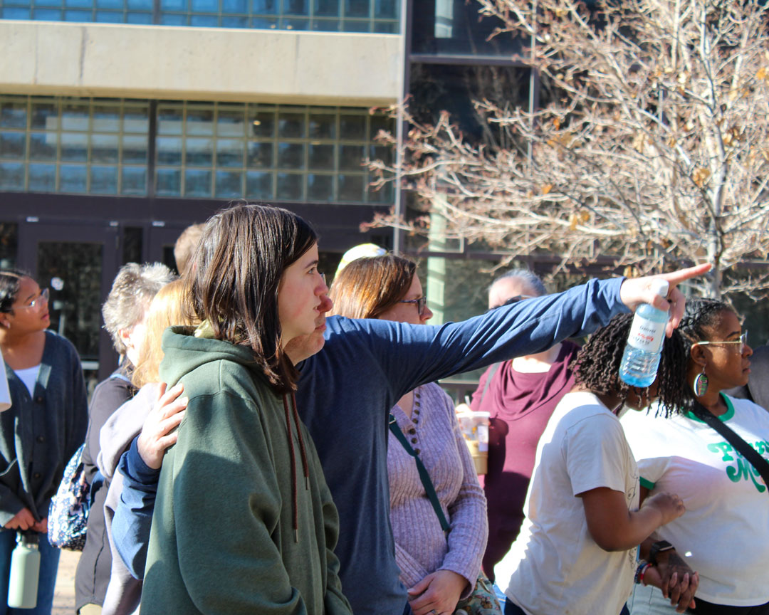 A guide pointing out a building during a campus tour