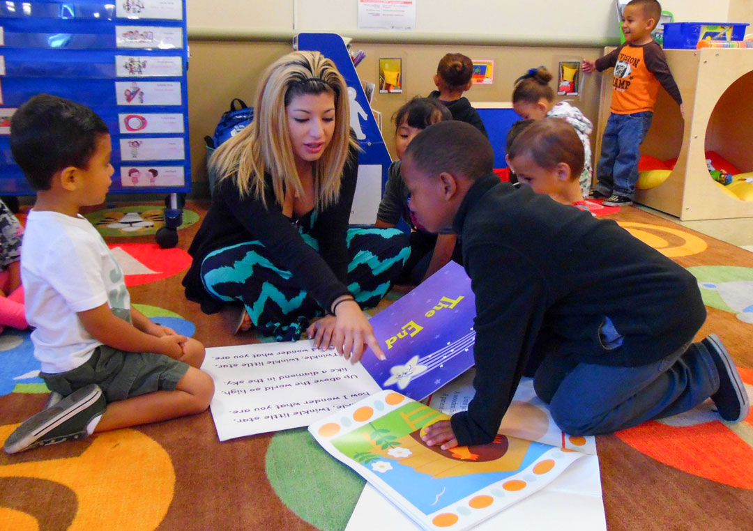 A teacher reading with preschoolers on a classroom rug