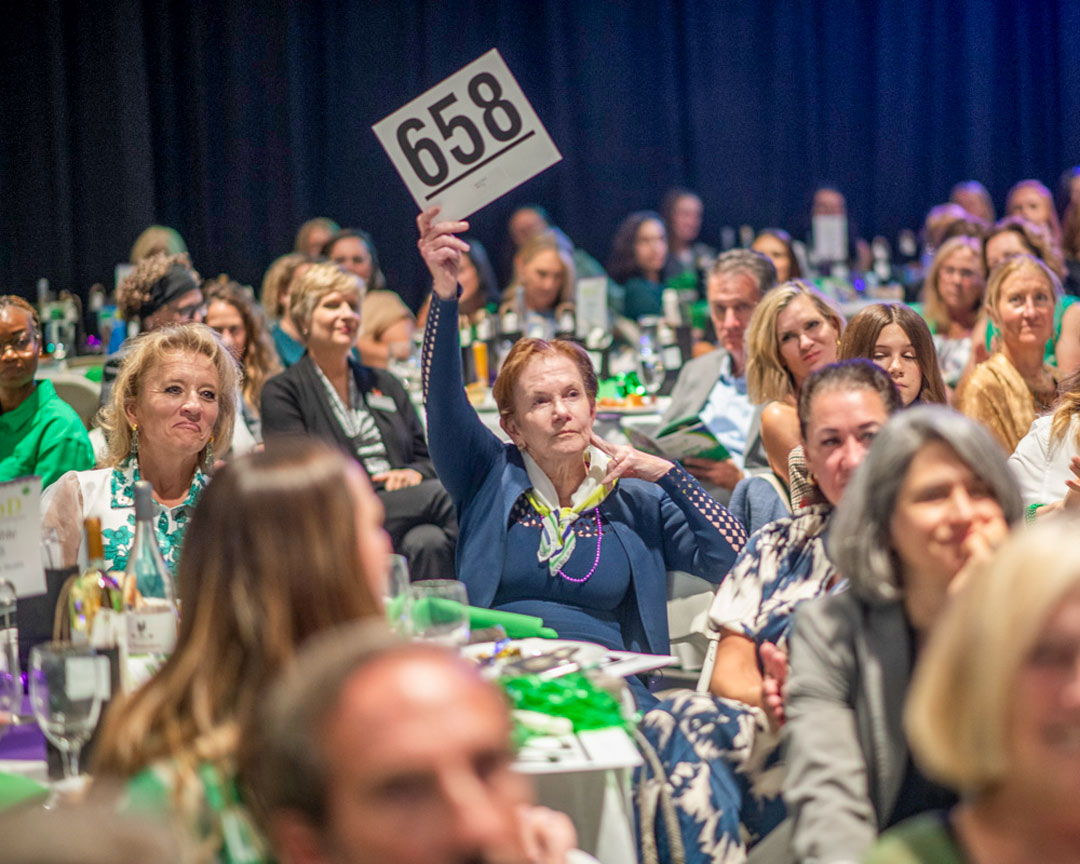 A guest raising bid paddle 658 during the event's paddle raise